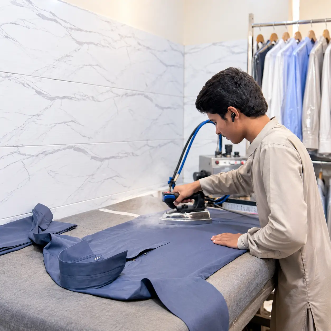 Dreams Dry Cleaners team member steam ironing a garment in Karachi